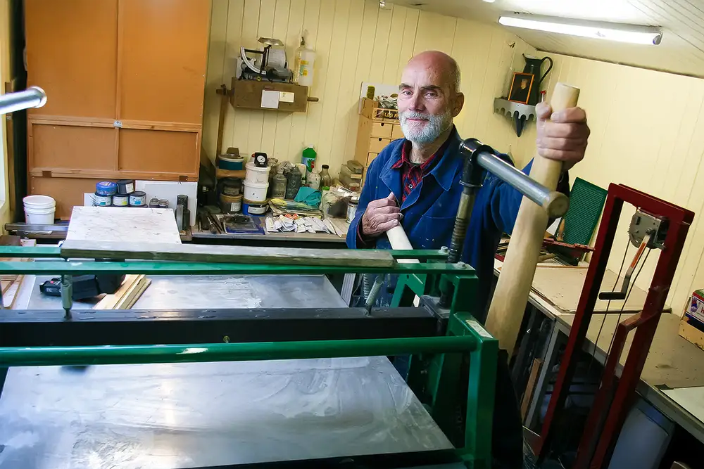 Helmut Böhm kunstenaar in etsen en lithografie in zijn atelier bij een pers